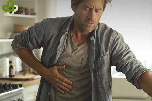 Мужчина на кухне держится за живот